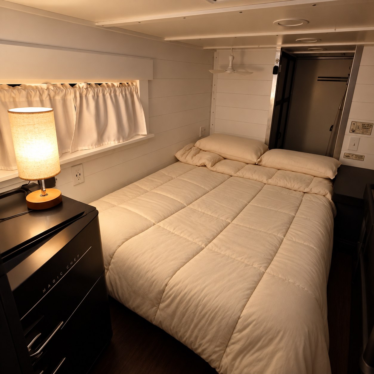 Cream bedding, white paneled walls, and warm lamplight inside Château Camion